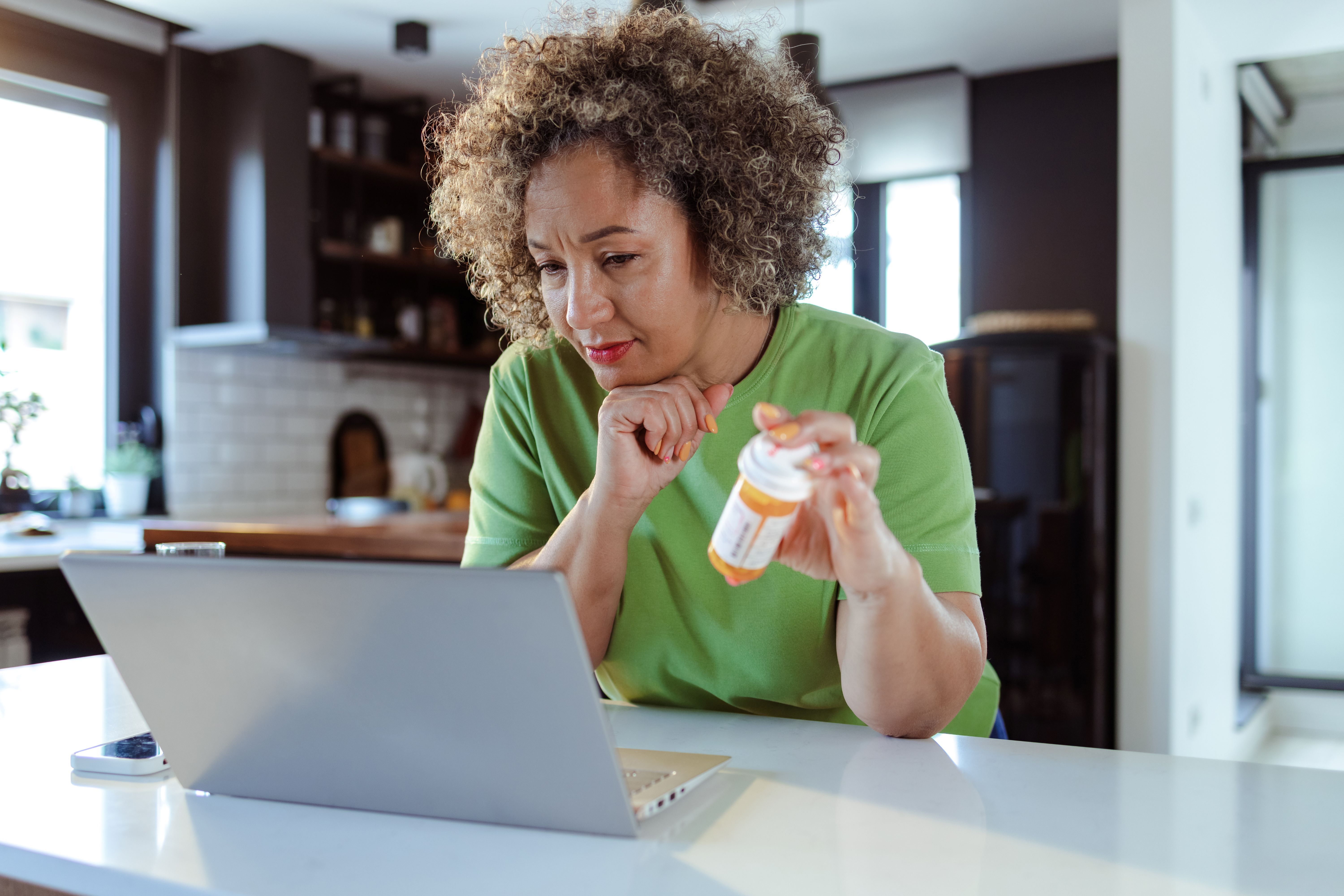  Alt Text: Women sitting at the table in the living room and searching information about medicine on the internet.