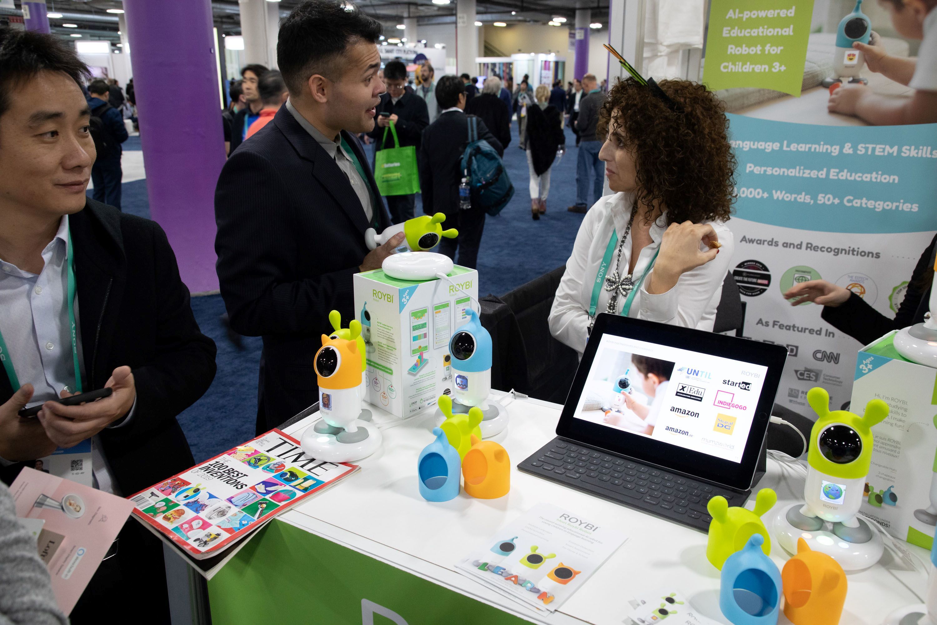 Alt Text: ROYBI exhibit boot at CES 2020 in Eureka Park. ROYBI representative speaking with attendee about ROYBI educational robot. 