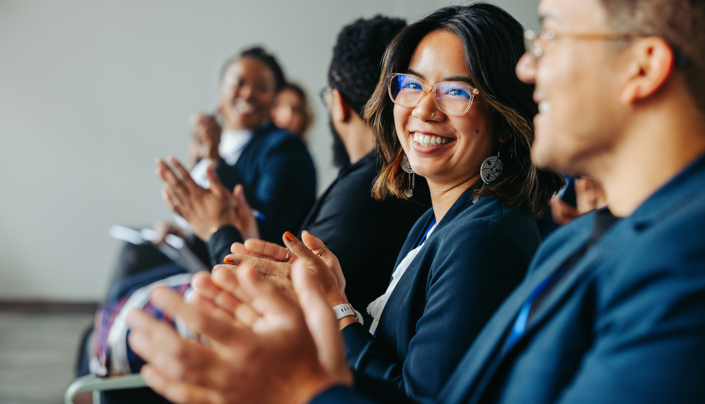 Alt text: Diverse colleagues clapping and smiling during business meeting 